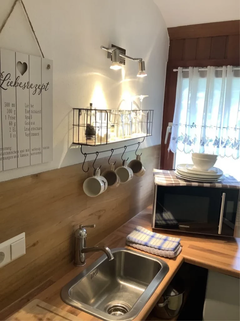 Schöne Mini-Kitchenette im Apartment Romantik des Gästehaus Sandvoss. Komplett ausgestattet mit Mikrowelle, Kühlschrank, Einzelkochplatte, Mikrowelle, Wasserkocher, Kaffeemaschine, sowie das Geschirr und die entsprechenden Utensilien zum Kochen.